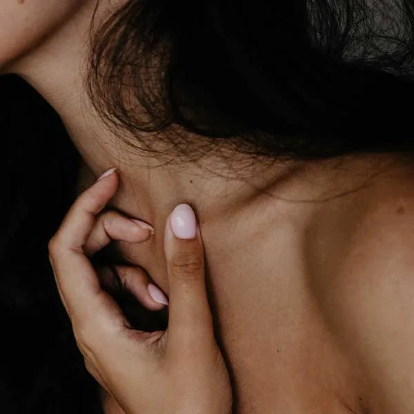 Woman's hand resting on her décolletage 