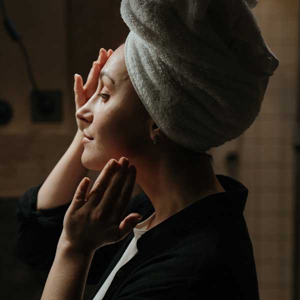 Woman applying skincare to face in bathroom