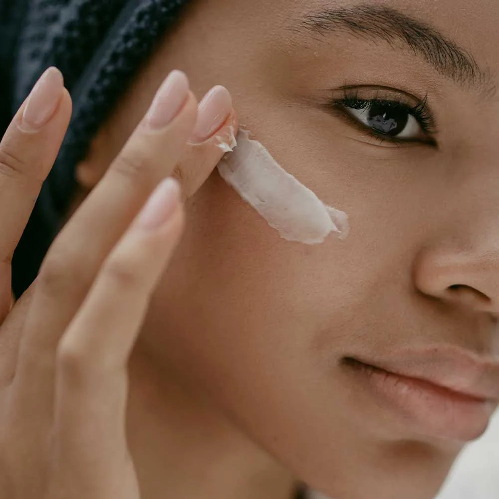 Woman sitting in bath with skin care products on her face