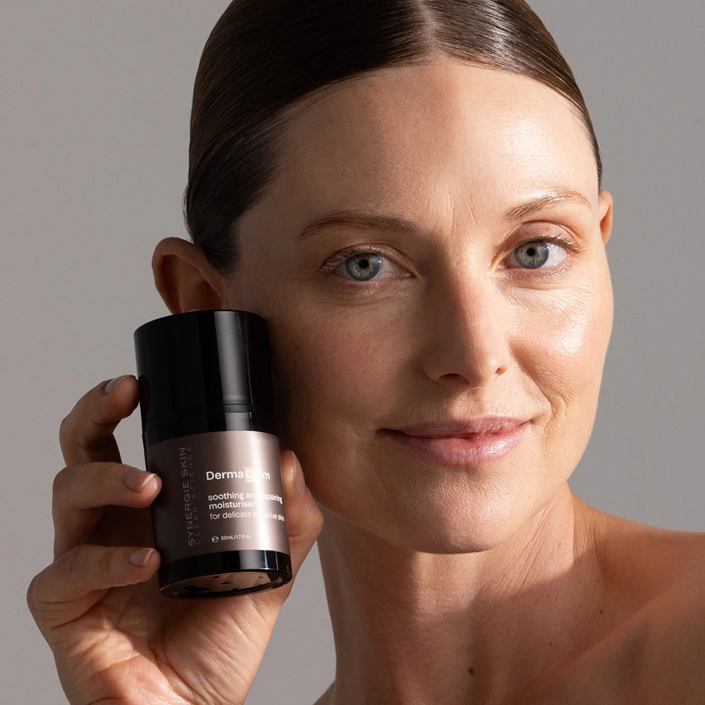 Model holding DermaCalm bottle next to her face