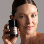 Model holding DermaCalm bottle next to her face