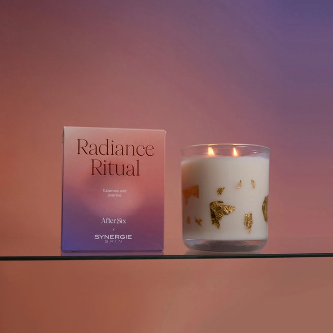Radiance Ritual Candle is lit and is sitting next to the packaging it will be delivered in